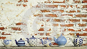Ceramic teapot with old vintage brick wall background.