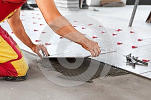 Ceramic Tiles. Tiler placing ceramic wall tile in position over adhesive with lash tile leveling system