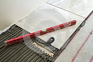 Ceramic tiles and tools for tiler. Home improvement, renovation - ceramic tile floor adhesive, mortar, level.