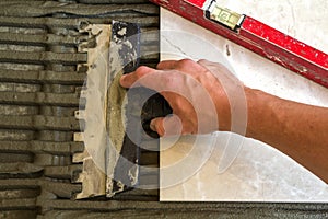 Ceramic tiles and tools for tiler. Worker hand installing floor tiles. Home improvement, renovation - ceramic tile floor adhesive,