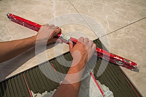 Ceramic tiles and tools for tiler. Worker hand installing floor tiles. Home improvement, renovation - ceramic tile floor adhesive,