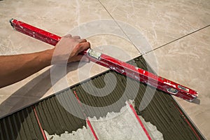 Ceramic tiles and tools for tiler. Worker hand installing floor tiles. Home improvement, renovation - ceramic tile floor adhesive,