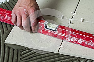 Ceramic tiles and tools for tiler. Worker hand installing floor tiles. Home improvement, renovation - ceramic tile floor adhesive,
