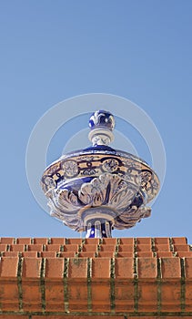 Ceramic top vase placed over brick wall