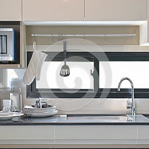 Ceramic ware and utensils setting up next to sink in modern kitchen at home