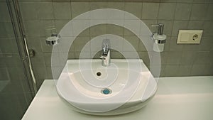 Ceramic washbasin with hot and cold faucet in luxury hotel bathroom.