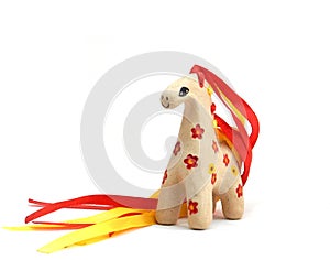 Ceramic whistle horse with a mane of yellow and red ribbons and painted with flowers  on a white background