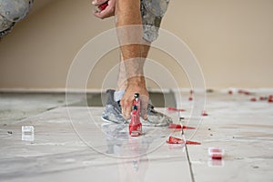 Ceramic white floor tiles laid over adhesive with a tile leveling system