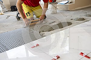 Ceramic white floor tiles laid over adhesive with a tile leveling system