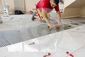 Ceramic white floor tiles laid over adhesive with a tile leveling system