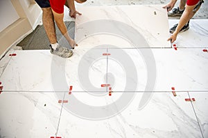 Ceramic white floor tiles laid over adhesive with a tile leveling system