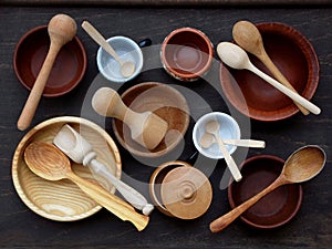 Ceramic, wooden, clay empty handmade bowl, cup and spoon on dark background. Pottery earthenware utensil, kitchenware.