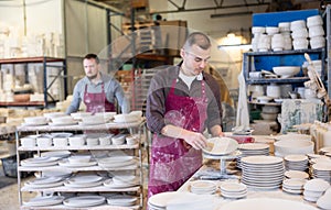 Ceramicist using sponge to clean pottery plates in artisanal workshop photo