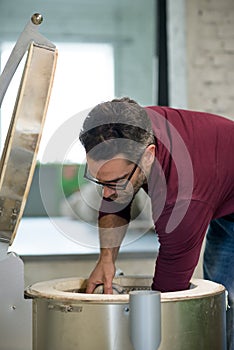 Ceramist Dressed in an Apron Placing Clay Sculpture in Electric Oven.