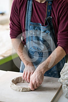 Ceramist Dressed in an Apron Working with Raw Clay in Bright Ceramic Workshop.