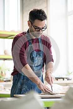 Ceramist Dressed in an Apron Working with Raw Clay in Bright Ceramic Workshop.