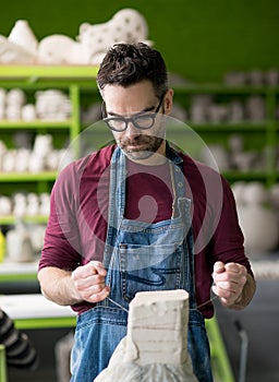 Ceramist Dressed in an Apron Working with Raw Clay in Bright Ceramic Workshop.