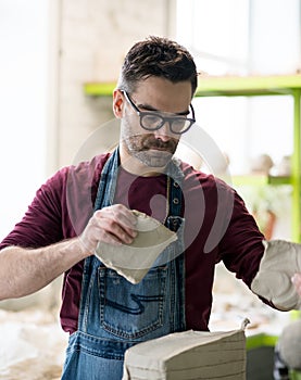 Ceramist Dressed in an Apron Working with Raw Clay in Bright Ceramic Workshop.