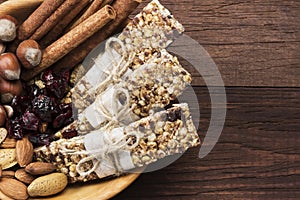 Cereal bars with nuts, berries and cinnamon on a wooden background. Top view, copy space. Food background