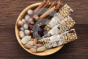 Cereal bars with nuts, berries and cinnamon on a wooden background. Top view. Food background