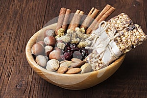 Cereal bars with nuts, berries and cinnamon on a wooden background