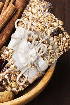 Cereal bars with nuts, berries and cinnamon on a wooden background