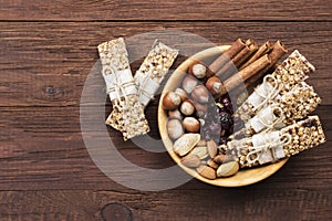 Cereal bars with nuts, berries and cinnamon on a wooden background. Top view, copy space. Food background