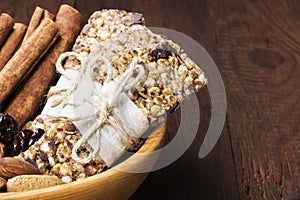 Cereal bars with nuts, berries and cinnamon on a wooden background. Copy space. Food background