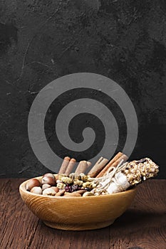 Cereal bars with nuts, berries and cinnamon on a wooden background