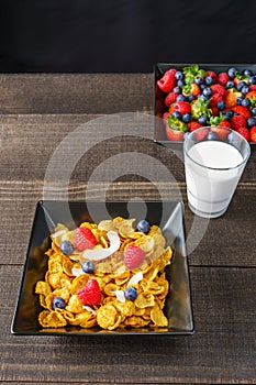 Cereal and berries in a black square bowl Morning breakfast with milk.