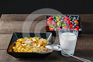 Cereal and berries in a black square bowl Morning breakfast with milk.