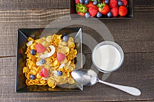 Cereal and berries in a black square bowl Morning breakfast with milk.