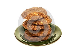 Cereal bio biscuits with chocolate chips and nuts isolated on a green plate on white background