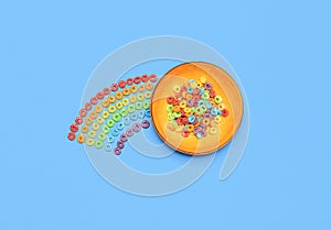 Cereal bowl isolated on blue background. Rainbow fruit-flavored ring cereals, top view