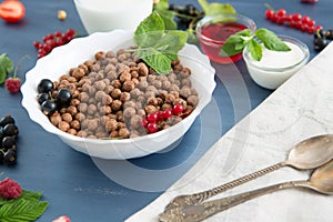 Cereal chocolate balls in bowl with milk on rustic wooden table Healthy tasty breakfast chocolate balls with