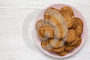 Cereal cookies on a pink plate on a white wooden background, top view. Flat lay, overhead, from above. Space for text