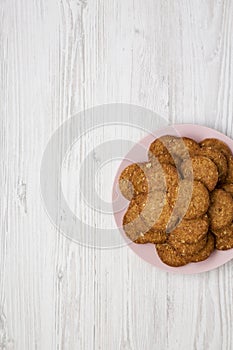 Cereal cookies on a pink plate on a white wooden table top view. Flat lay, overhead, from above. Space for text