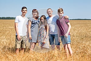 Cereal farmer family with wife, two teenage sons and preteen daughter, long family portrait on yellow wheat field