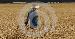 Cereal farming. woman farmer walking through the wheat crop field and check the harvest