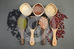 Cereal grains and Seeds beans useful for health in wood spoons on grey background.