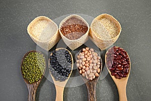 Cereal grains and Seeds beans useful for health in wood spoons on grey background.