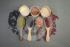 Cereal grains and Seeds beans useful for health in wood spoons on grey background.