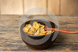 Cereal in wooden bowl with milk splash on blurred wooden