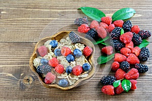 Cereals integral with seasonal forest berries in the wooden bowl and on the wood background. Proper nutrition, balanced diet