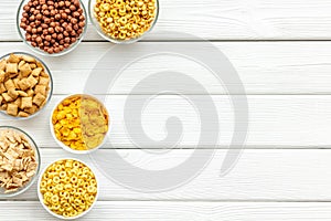 Cereals, oatflakes and cornflakes for healthy breakfast on white wooden background top view mock up photo