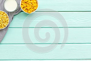 Cereals, oatflakes and cornflakes with milk for healthy breakfast on mint wooden background top view mock up photo