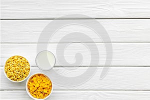 Cereals, oatflakes and cornflakes with milk for healthy breakfast on white wooden background top view mock up photo