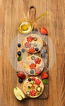 Cereals sandwiches with peanut butter with fruits and berries with honey on a wooden board, top view.