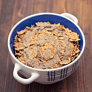 Cereals in white blue bowl on brown background