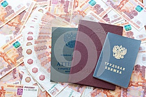 A certificate, a red diploma and a work book are on the five thousandth Russian rubles